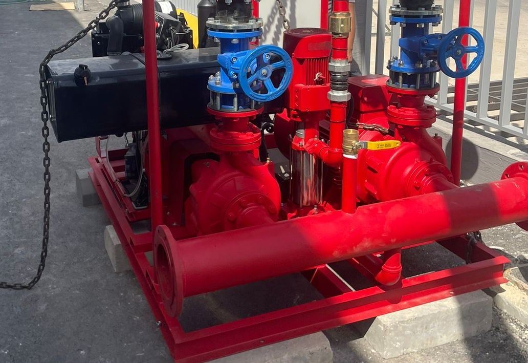 Large red fire-pump set with a diesel engine, two main pumps and a jockey pump, lowered onto blocks