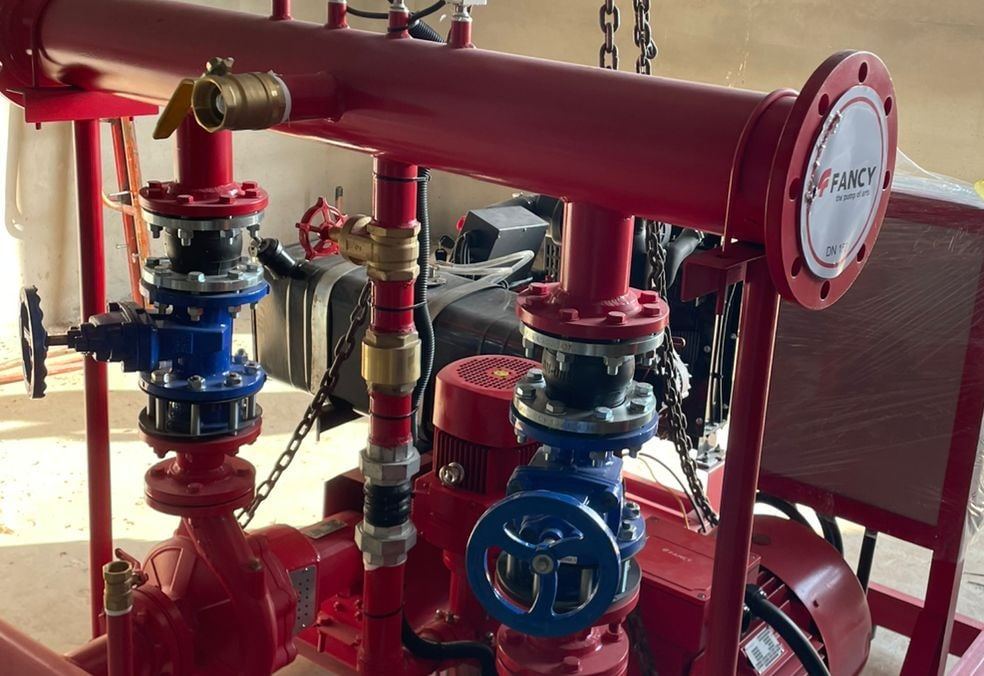 Close-up of a fire-pump set's red manifold, blue valves, jockey pump and controller