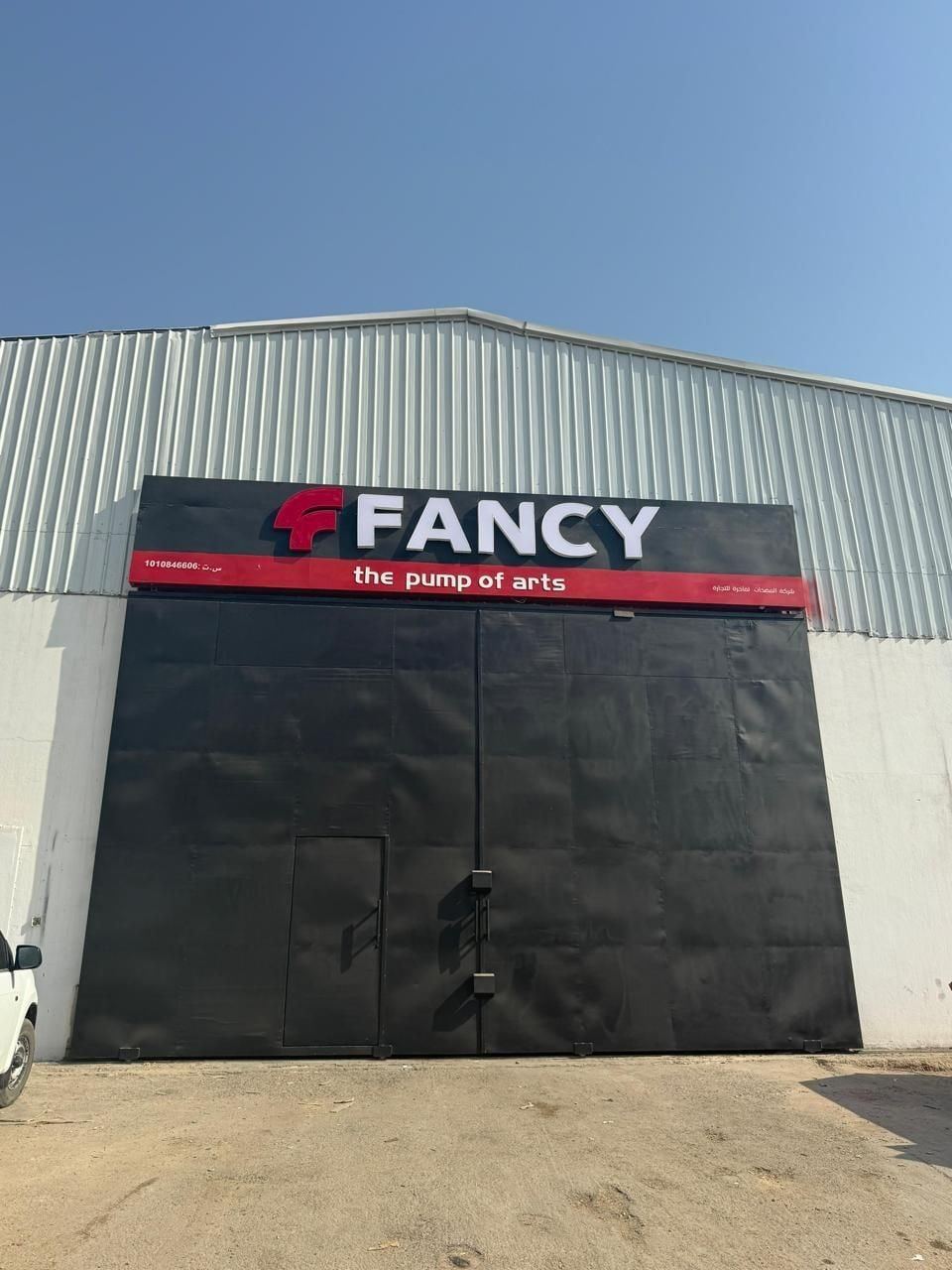 The assembly factory in Riyadh: a steel hall with a large black gate under a red-and-black FANCY sign